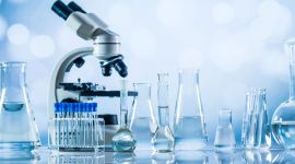 Labor mit Mikroskop, Reagenzgläsern und Glasgefäßen voller klarer Flüssigkeit – moderne Wissenschaft, Chemie und Forschung im Laborumfeld.